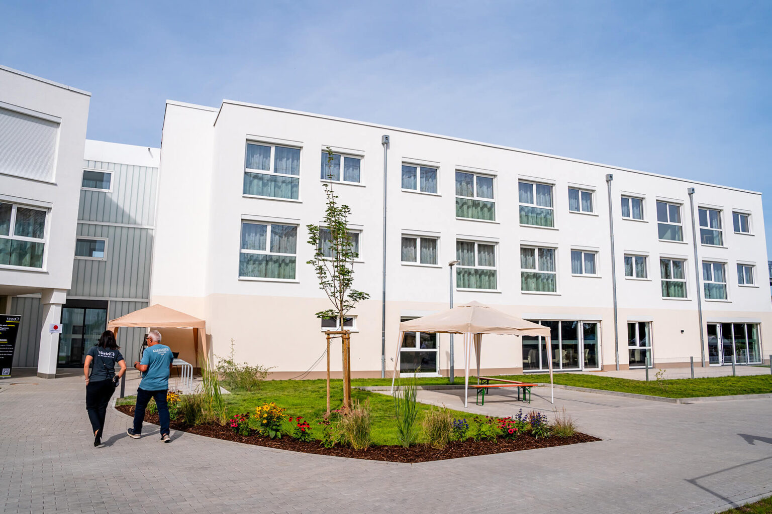 Pflegeheim in Stetten: Zwei Mitarbeiter spazieren durch den einladenden Außenbereich der Einrichtung.