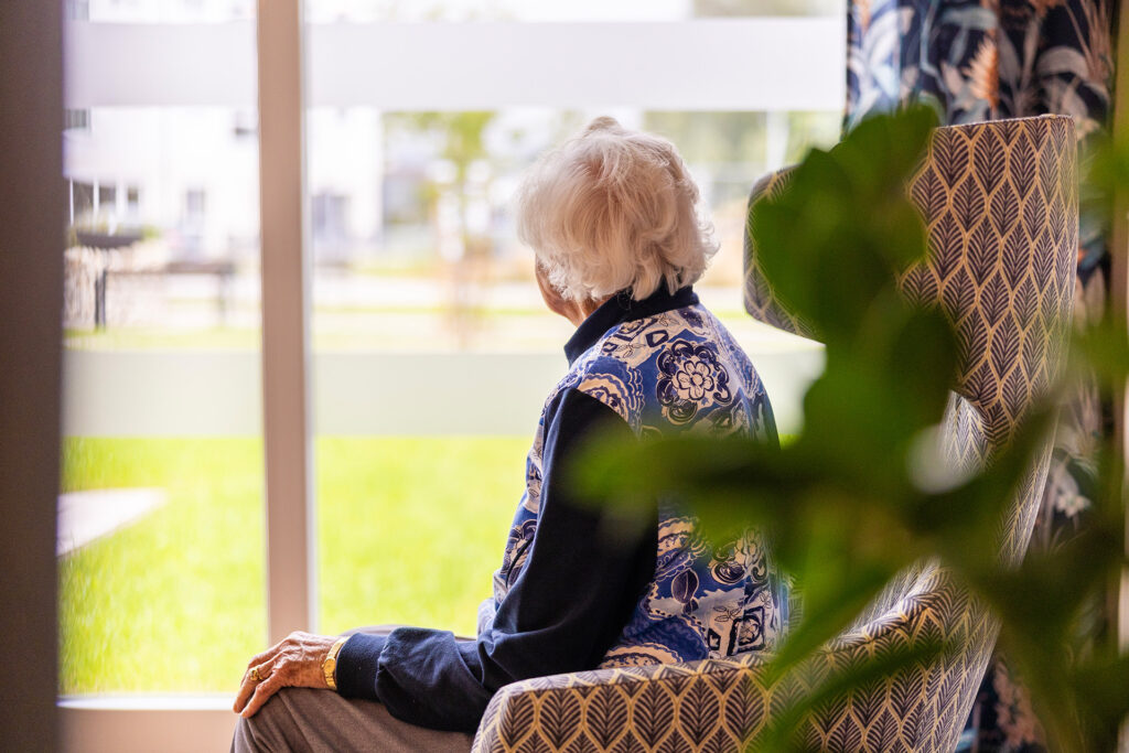 Pflegeheim mit Fokus auf Individualität: Seniorin genießt einen ruhigen Moment am Fenster.